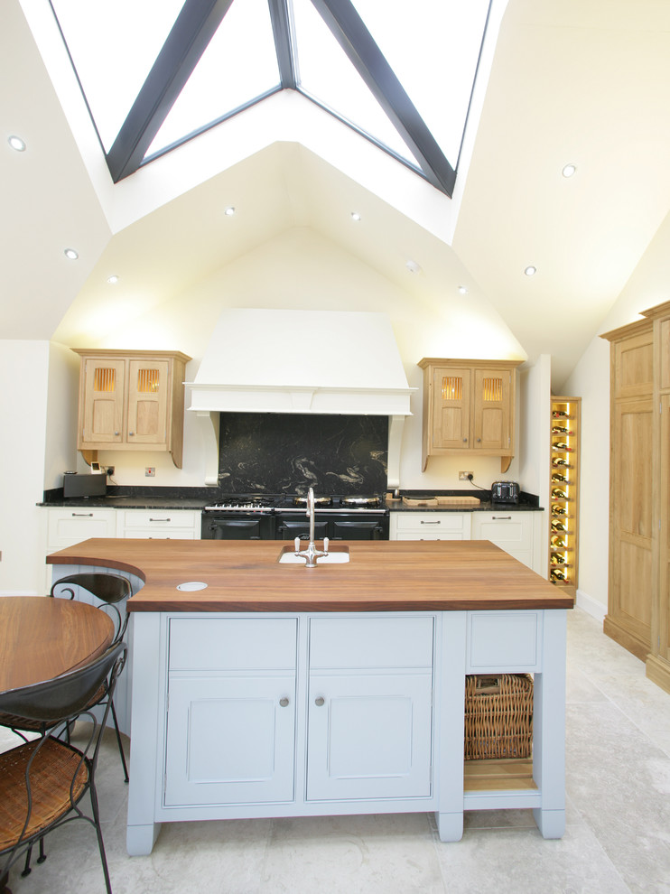 Large farmhouse kitchen/diner in Edinburgh with a built-in sink, beaded cabinets, blue cabinets, granite worktops, black splashback, stone slab splashback, integrated appliances and an island.