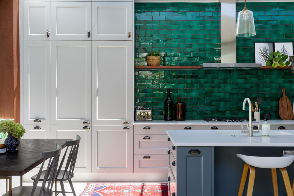 Offene Moderne Küche mit Schrankfronten im Shaker-Stil, Mineralwerkstoff-Arbeitsplatte, Küchenrückwand in Grün, Kücheninsel und grauem Boden in London