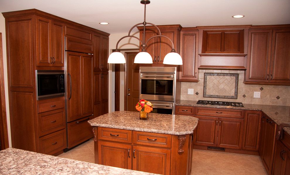 This is an example of a large traditional u-shaped kitchen/diner in St Louis with a submerged sink, raised-panel cabinets, medium wood cabinets, engineered stone countertops, metallic splashback, cement tile splashback, stainless steel appliances, ceramic flooring and an island.