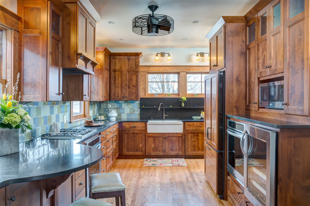 Bild på ett litet amerikanskt kök, med en rustik diskho, skåp i shakerstil, skåp i mellenmörkt trä, granitbänkskiva, flerfärgad stänkskydd, stänkskydd i keramik, rostfria vitvaror, mellanmörkt trägolv och brunt golv