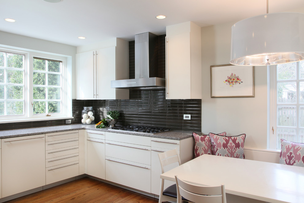 Medium sized contemporary u-shaped open plan kitchen in Philadelphia with glass tiled splashback, black splashback, flat-panel cabinets, white cabinets and medium hardwood flooring.