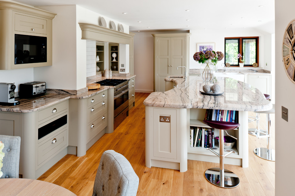 Inspiration for a medium sized traditional single-wall kitchen/diner in Surrey with a submerged sink, recessed-panel cabinets, green cabinets, granite worktops, metro tiled splashback, stainless steel appliances, light hardwood flooring, an island, brown floors and beige worktops.
