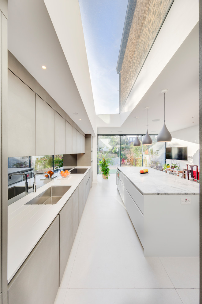 Idee per una cucina moderna di medie dimensioni con ante lisce, ante grigie, paraspruzzi a specchio, elettrodomestici in acciaio inossidabile, pavimento bianco e top bianco