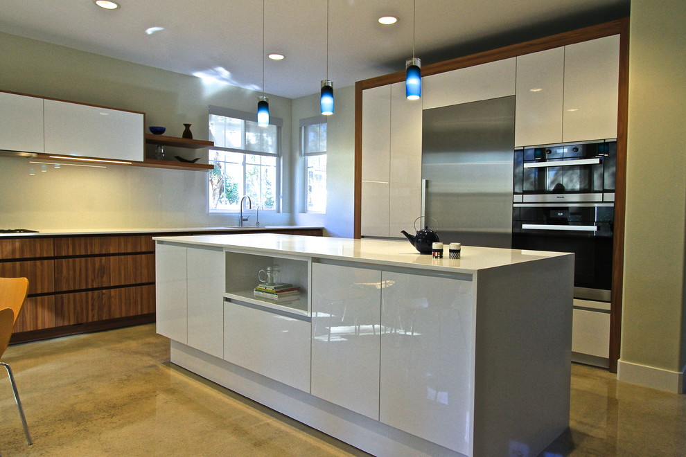 Modern inredning av ett mellanstort kök, med en undermonterad diskho, släta luckor, vita skåp, bänkskiva i koppar, vitt stänkskydd, glaspanel som stänkskydd, rostfria vitvaror, betonggolv och en köksö
