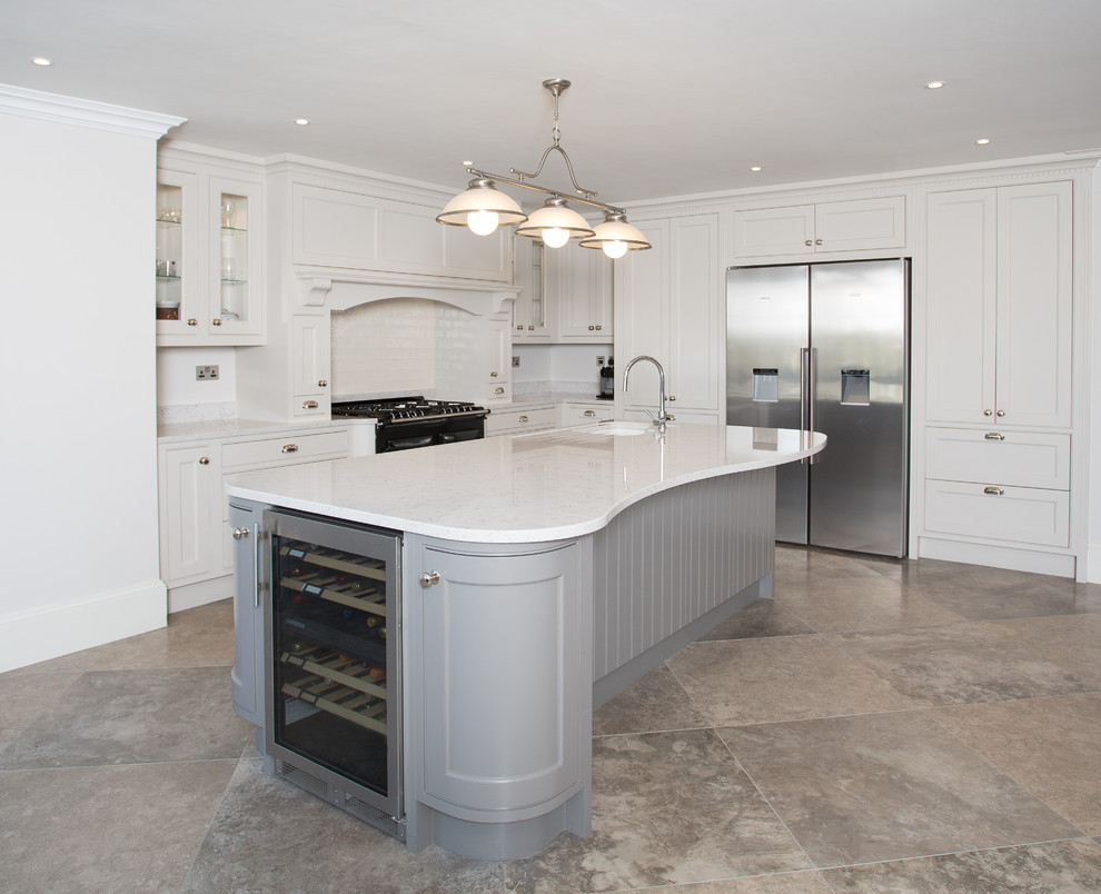 This is an example of a large traditional l-shaped enclosed kitchen in Dublin with a built-in sink, shaker cabinets, white cabinets, quartz worktops, white splashback, metro tiled splashback, stainless steel appliances, porcelain flooring and a breakfast bar.