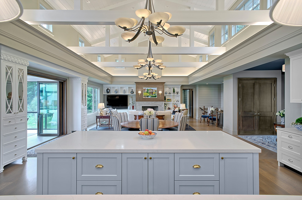 Design ideas for an expansive traditional l-shaped open plan kitchen in Grand Rapids with a submerged sink, shaker cabinets, blue cabinets, engineered stone countertops, blue splashback, ceramic splashback, stainless steel appliances, medium hardwood flooring, multiple islands, brown floors, white worktops and a timber clad ceiling.