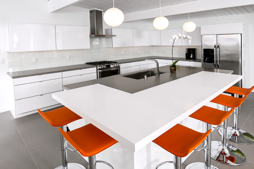 Example of a large minimalist ceramic tile kitchen design in Los Angeles with an undermount sink, flat-panel cabinets, white cabinets, white backsplash, glass tile backsplash, stainless steel appliances and an island