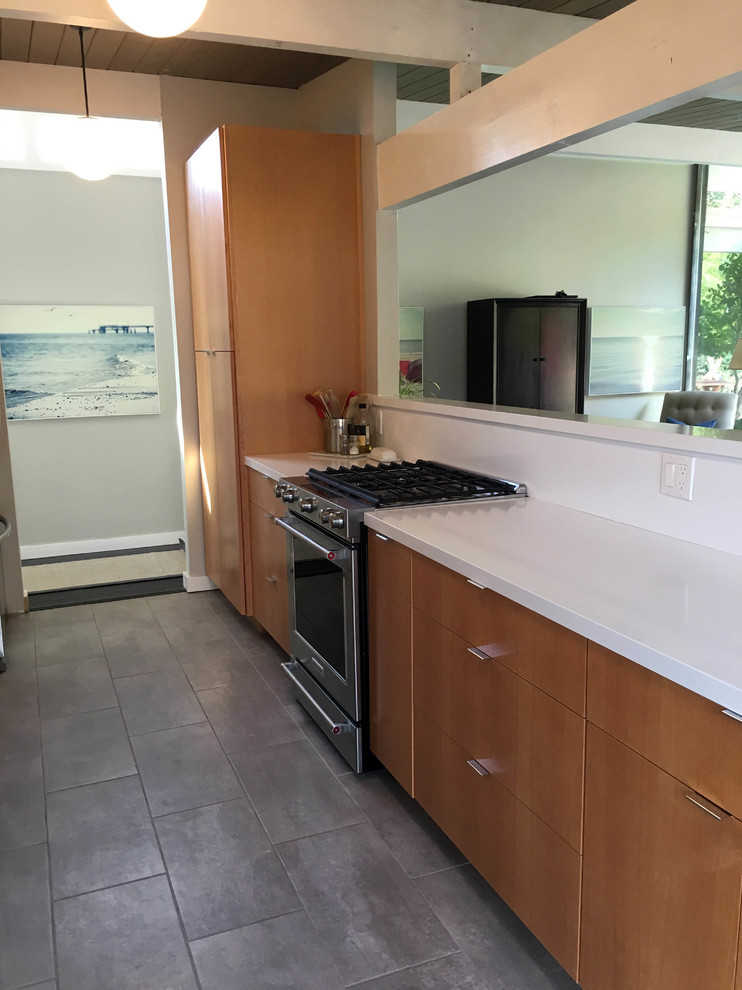 This is an example of a medium sized modern galley open plan kitchen in San Francisco with a submerged sink, flat-panel cabinets, light wood cabinets, composite countertops, white splashback, stone slab splashback, stainless steel appliances, ceramic flooring and no island.