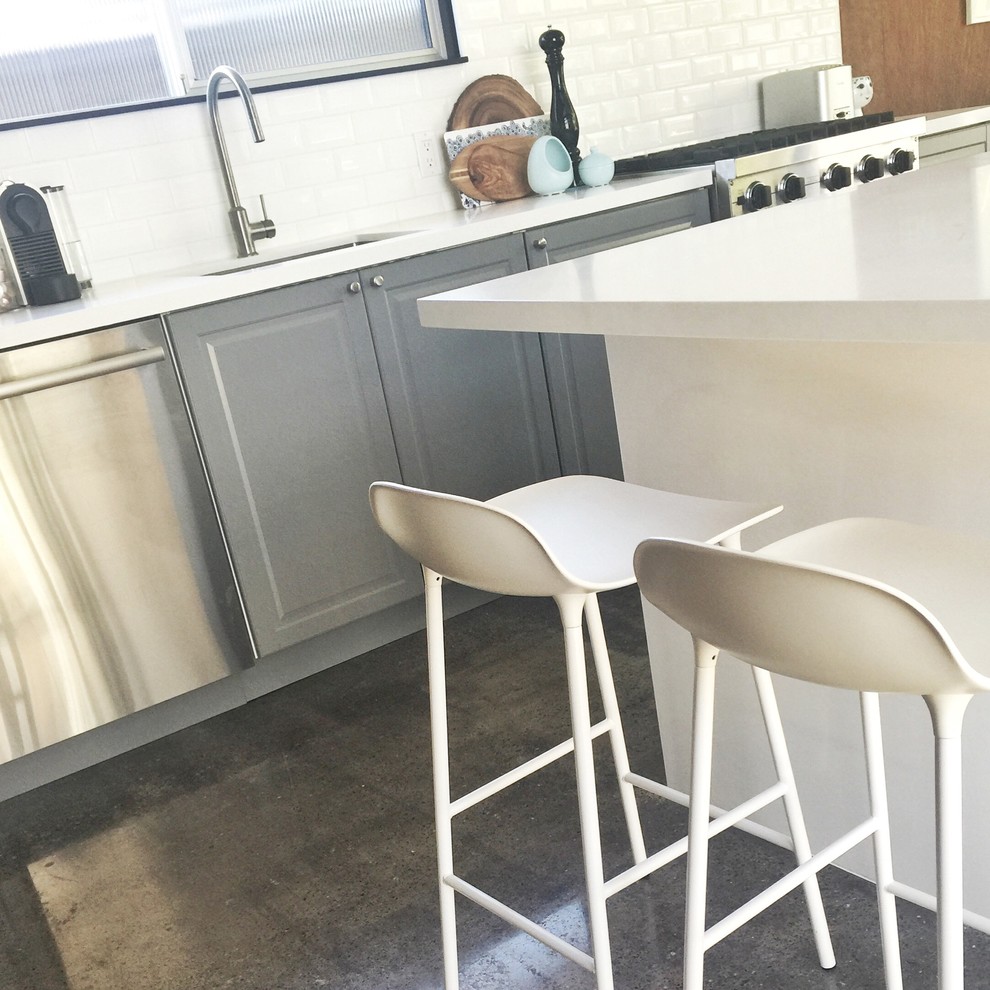 Photo of a medium sized retro single-wall kitchen/diner in San Francisco with a submerged sink, recessed-panel cabinets, grey cabinets, quartz worktops, white splashback, ceramic splashback, stainless steel appliances, concrete flooring and an island.