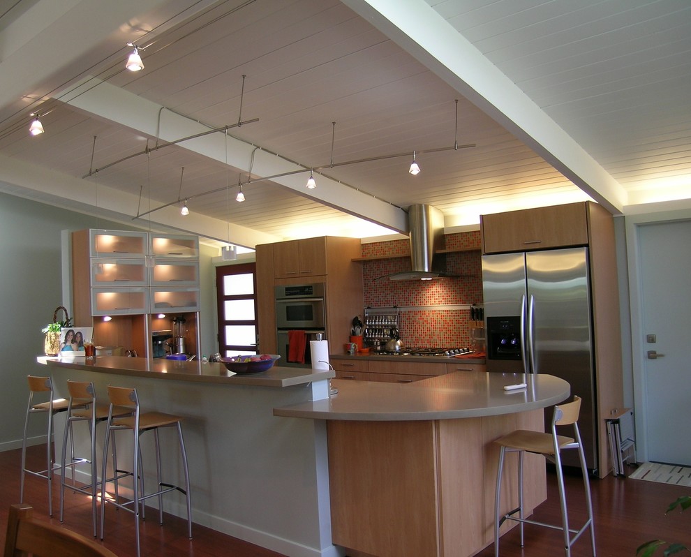 Bild på ett mellanstort eklektiskt kök, med en undermonterad diskho, släta luckor, skåp i mellenmörkt trä, bänkskiva i koppar, orange stänkskydd, stänkskydd i glaskakel, rostfria vitvaror, mellanmörkt trägolv och en köksö