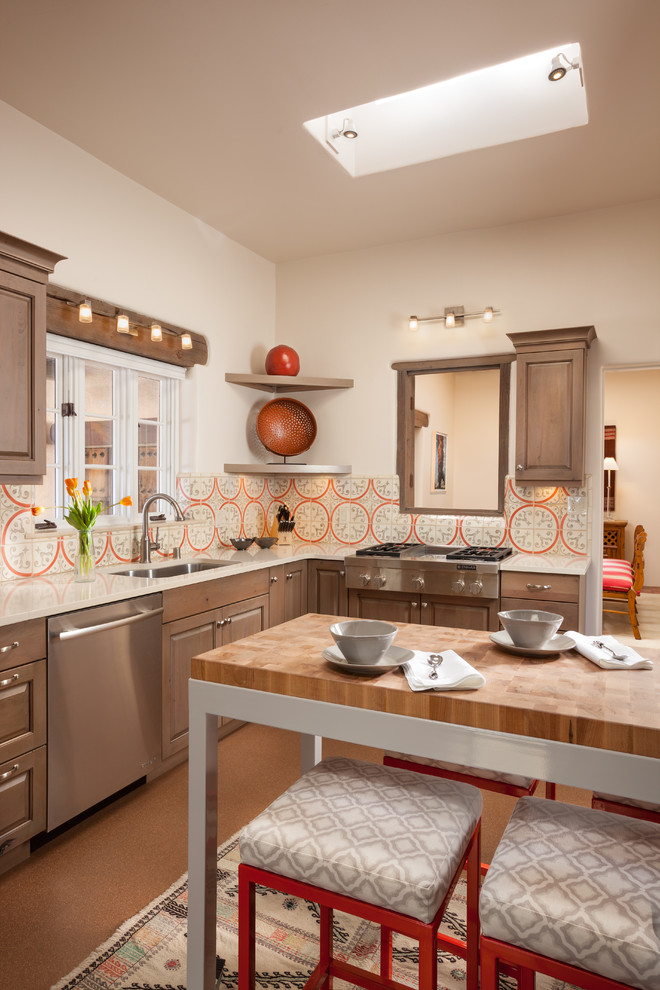 Mediterrane Küche in L-Form mit Unterbauwaschbecken, profilierten Schrankfronten, hellbraunen Holzschränken, bunter Rückwand, Küchengeräten aus Edelstahl und Kücheninsel in Albuquerque