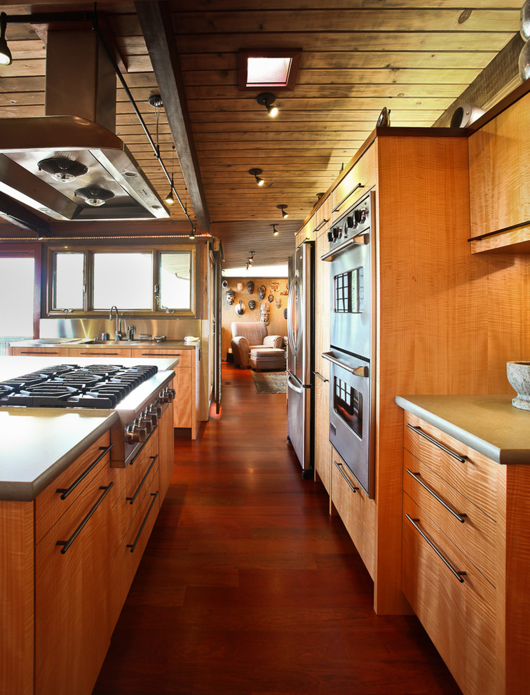 Immagine di una cucina moderna con ante lisce, ante in legno chiaro, top in quarzo composito e elettrodomestici in acciaio inossidabile