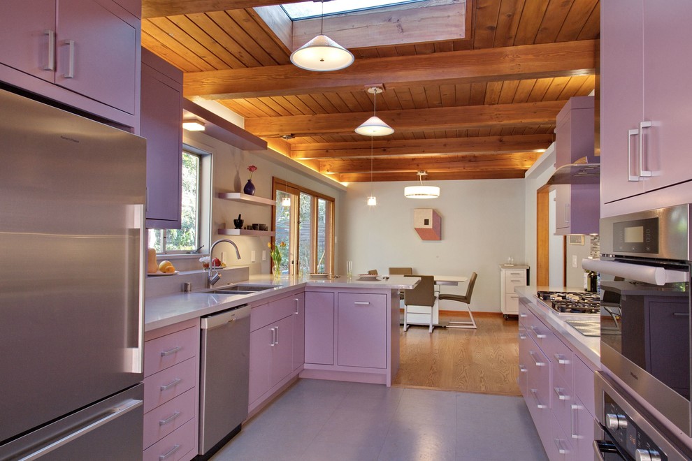 Foto på ett mellanstort funkis lila kök, med en undermonterad diskho, rostfria vitvaror, grått golv, släta luckor, lila skåp, bänkskiva i kvarts, flerfärgad stänkskydd, stänkskydd i glaskakel och en halv köksö