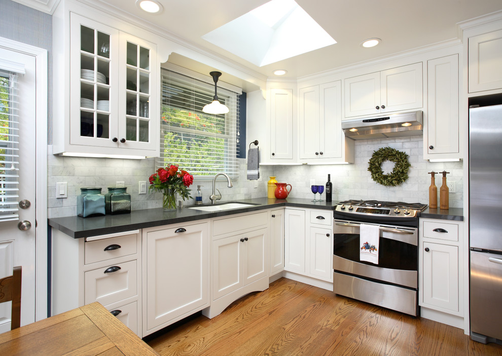 Example of a large transitional medium tone wood floor kitchen design in San Francisco with beaded inset cabinets, black cabinets, quartzite countertops and white backsplash