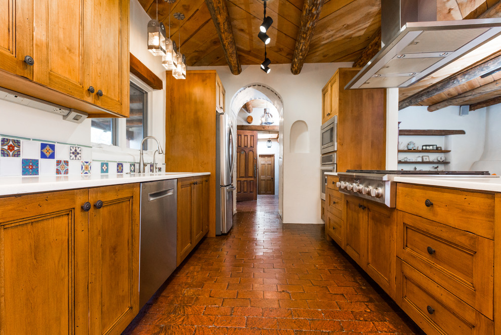 Exempel på ett mellanstort amerikanskt beige beige kök, med en undermonterad diskho, skåp i shakerstil, skåp i mellenmörkt trä, bänkskiva i kvarts, flerfärgad stänkskydd, stänkskydd i porslinskakel, rostfria vitvaror, tegelgolv, en halv köksö och rött golv