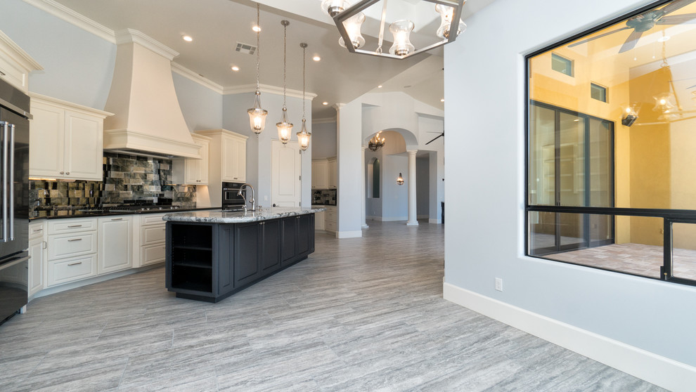 Example of a large transitional single-wall porcelain tile and gray floor eat-in kitchen design in Phoenix with raised-panel cabinets, white cabinets, granite countertops, an island, an undermount sink, metallic backsplash, mirror backsplash and stainless steel appliances
