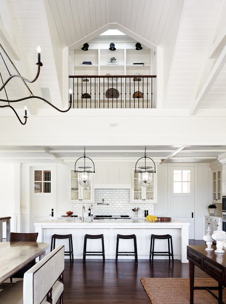L-shaped dark wood floor open concept kitchen photo in San Francisco with glass-front cabinets, white cabinets, white backsplash, subway tile backsplash, stainless steel appliances and an island