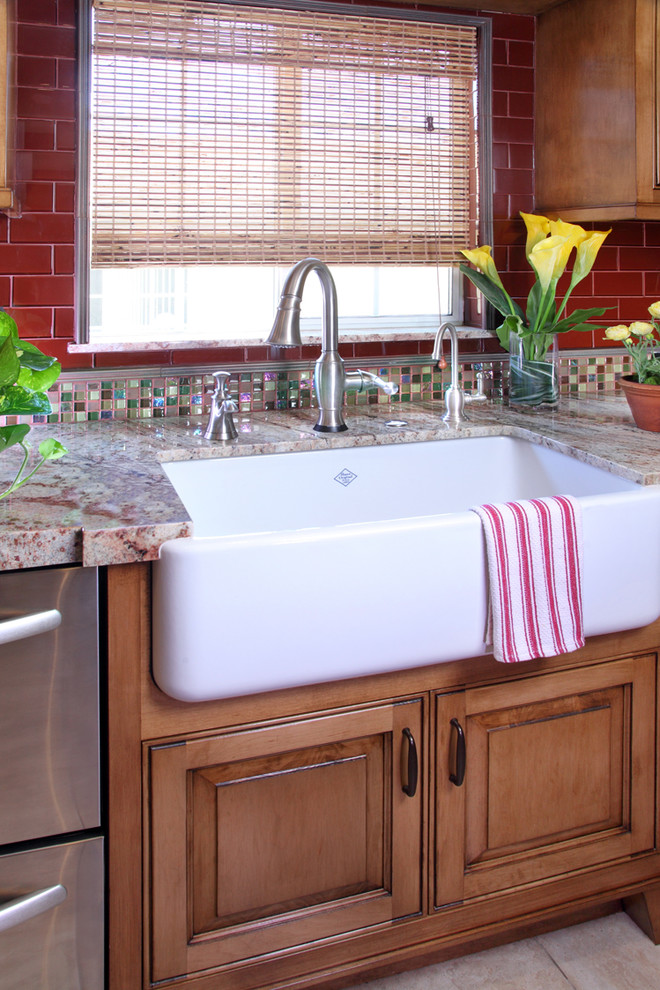 Exempel på ett lantligt kök, med en rustik diskho, luckor med upphöjd panel, skåp i mellenmörkt trä, granitbänkskiva, rött stänkskydd, stänkskydd i glaskakel, rostfria vitvaror och klinkergolv i porslin