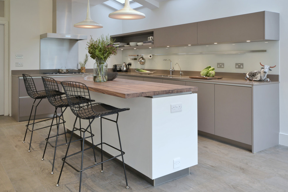 Medium sized contemporary l-shaped kitchen/diner in London with a submerged sink, flat-panel cabinets, grey cabinets, glass sheet splashback, an island and grey floors.