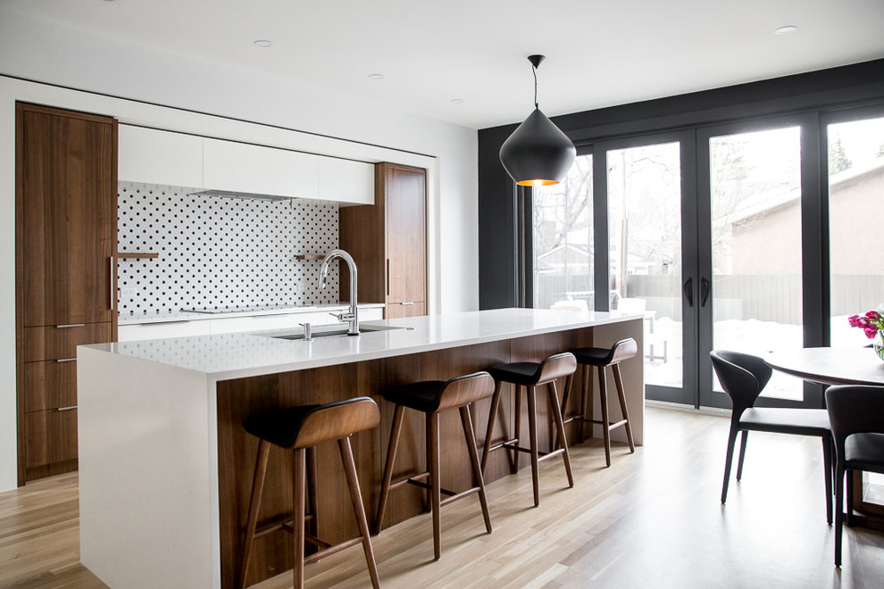 Eat-in kitchen - contemporary galley light wood floor and beige floor eat-in kitchen idea in Calgary with an undermount sink, flat-panel cabinets, dark wood cabinets, multicolored backsplash, paneled appliances, an island and white countertops