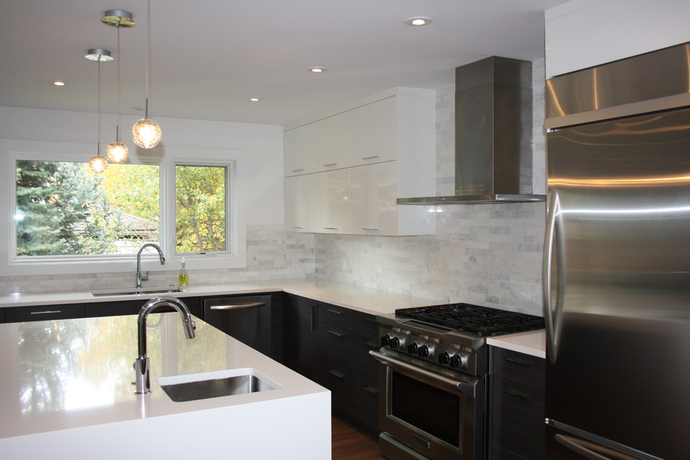 This is an example of a large modern u-shaped kitchen/diner in Calgary with a submerged sink, flat-panel cabinets, white cabinets, engineered stone countertops, grey splashback, stone tiled splashback, stainless steel appliances, medium hardwood flooring and an island.