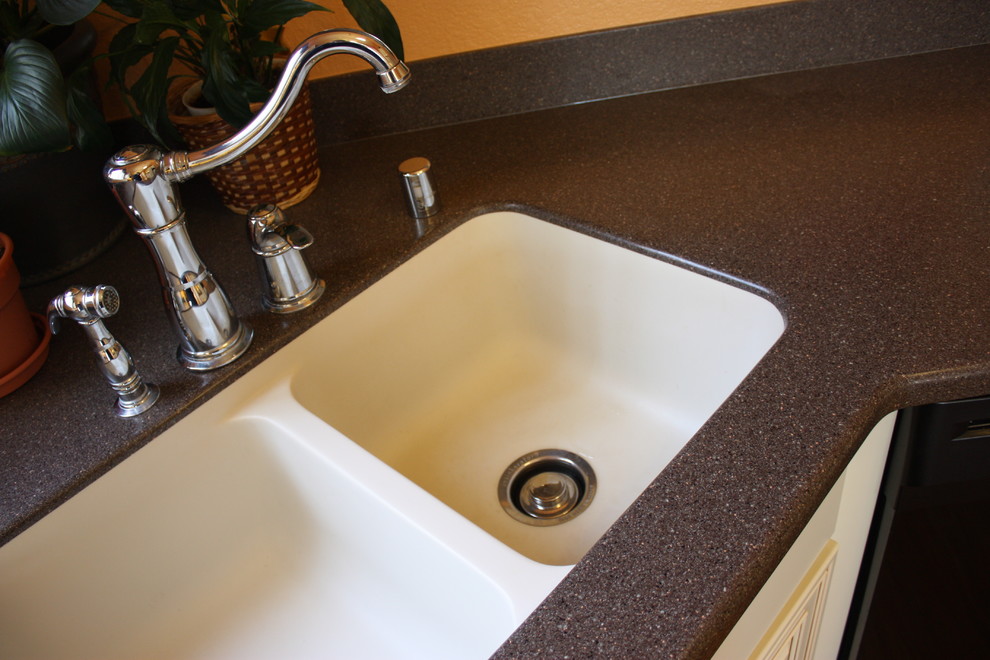 Large elegant u-shaped medium tone wood floor and brown floor eat-in kitchen photo in Albuquerque with an integrated sink, raised-panel cabinets, white cabinets, solid surface countertops, gray backsplash, black appliances and brown countertops