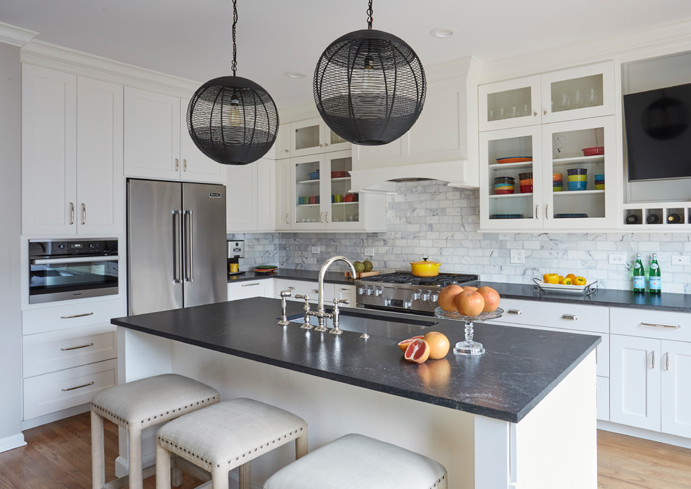Design ideas for a traditional l-shaped kitchen in Chicago with a submerged sink, shaker cabinets, white cabinets, grey splashback, stainless steel appliances, light hardwood flooring, an island and grey worktops.