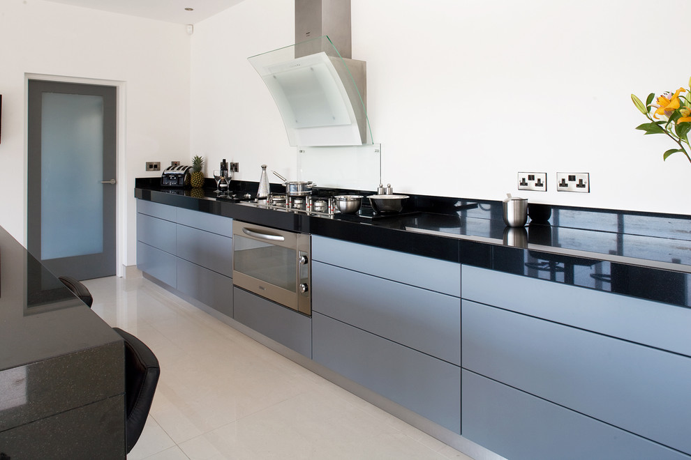 Moderne Küche mit Küchengeräten aus Edelstahl, flächenbündigen Schrankfronten und grauen Schränken in Sonstige