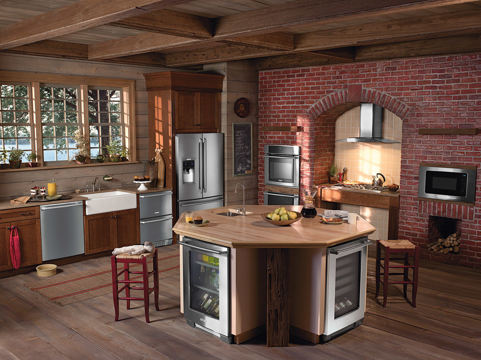 Lantlig inredning av ett avskilt, mellanstort u-kök, med en rustik diskho, luckor med infälld panel, skåp i mellenmörkt trä, träbänkskiva, rostfria vitvaror och en köksö