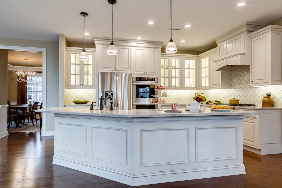 Kitchen - large traditional l-shaped medium tone wood floor and brown floor kitchen idea in Philadelphia with raised-panel cabinets, white cabinets, white backsplash, porcelain backsplash, stainless steel appliances and an island