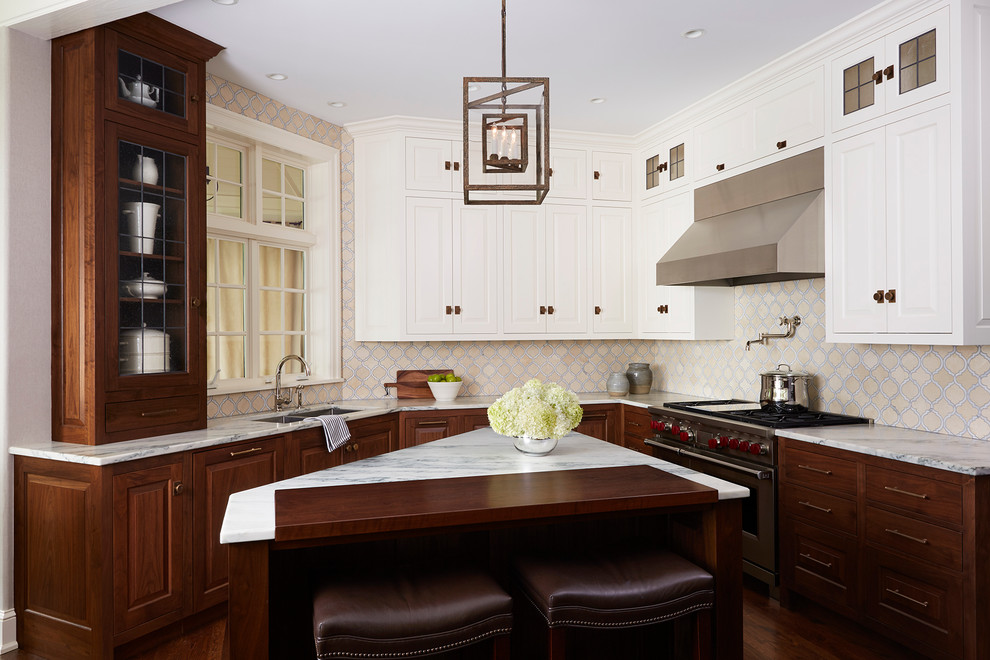 Klassische Küche mit Doppelwaschbecken, profilierten Schrankfronten, weißen Schränken, bunter Rückwand, Küchengeräten aus Edelstahl, dunklem Holzboden und Kücheninsel in Minneapolis