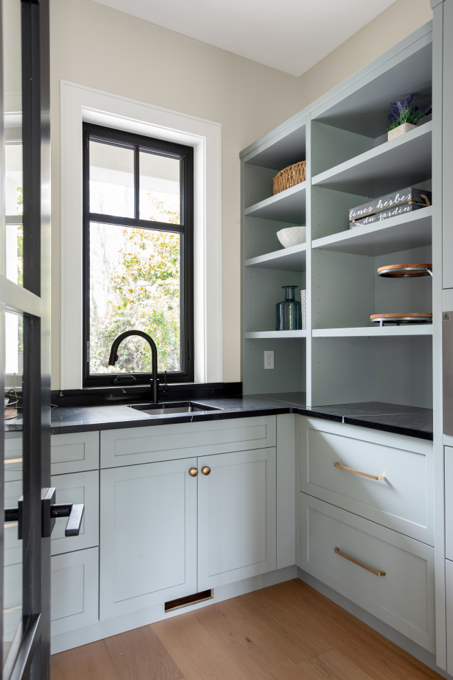 Foto di una cucina ad U chic di medie dimensioni con lavello sottopiano, ante in stile shaker, ante blu, pavimento in legno massello medio, pavimento beige e top nero