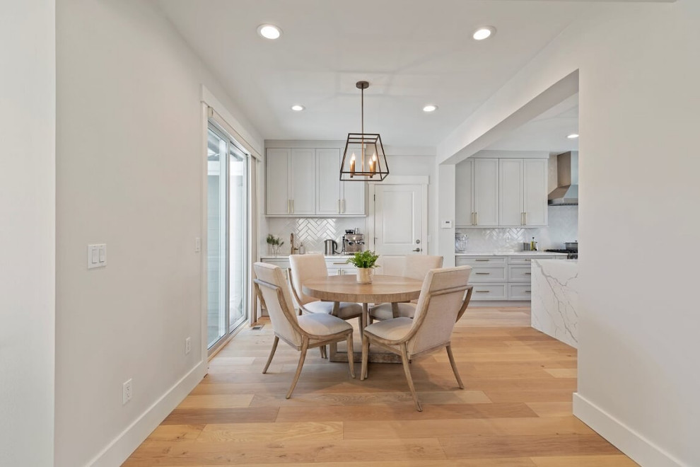 Photo of an expansive classic l-shaped kitchen/diner in Seattle with a submerged sink, shaker cabinets, grey cabinets, engineered stone countertops, white splashback, ceramic splashback, stainless steel appliances, light hardwood flooring, an island, beige floors and white worktops.