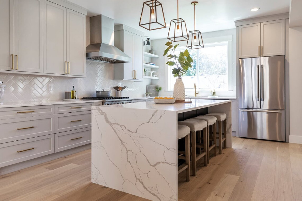 Inspiration for a huge transitional l-shaped light wood floor and beige floor eat-in kitchen remodel in Seattle with an undermount sink, shaker cabinets, gray cabinets, quartz countertops, white backsplash, ceramic backsplash, stainless steel appliances, an island and white countertops