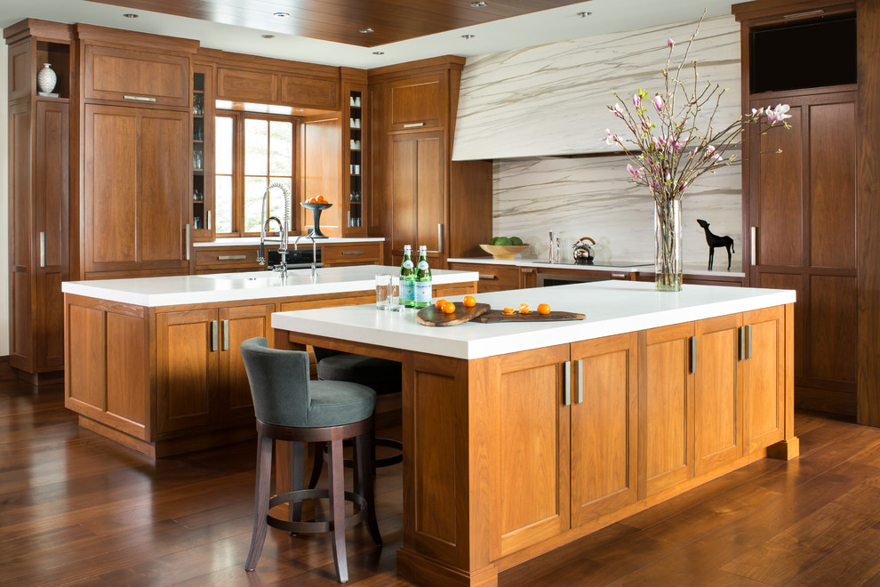 Photo of a classic kitchen in Denver with shaker cabinets, dark wood cabinets, white splashback, marble splashback, dark hardwood flooring, multiple islands and brown floors.