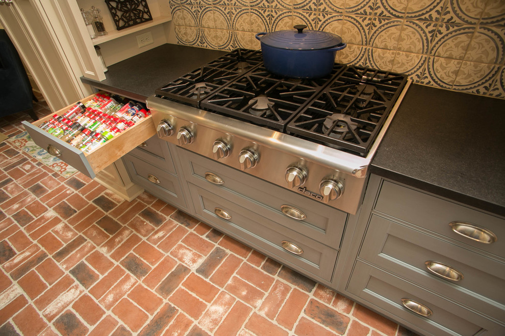 Esempio di una cucina classica di medie dimensioni con lavello sottopiano, ante con riquadro incassato, elettrodomestici in acciaio inossidabile e pavimento in mattoni