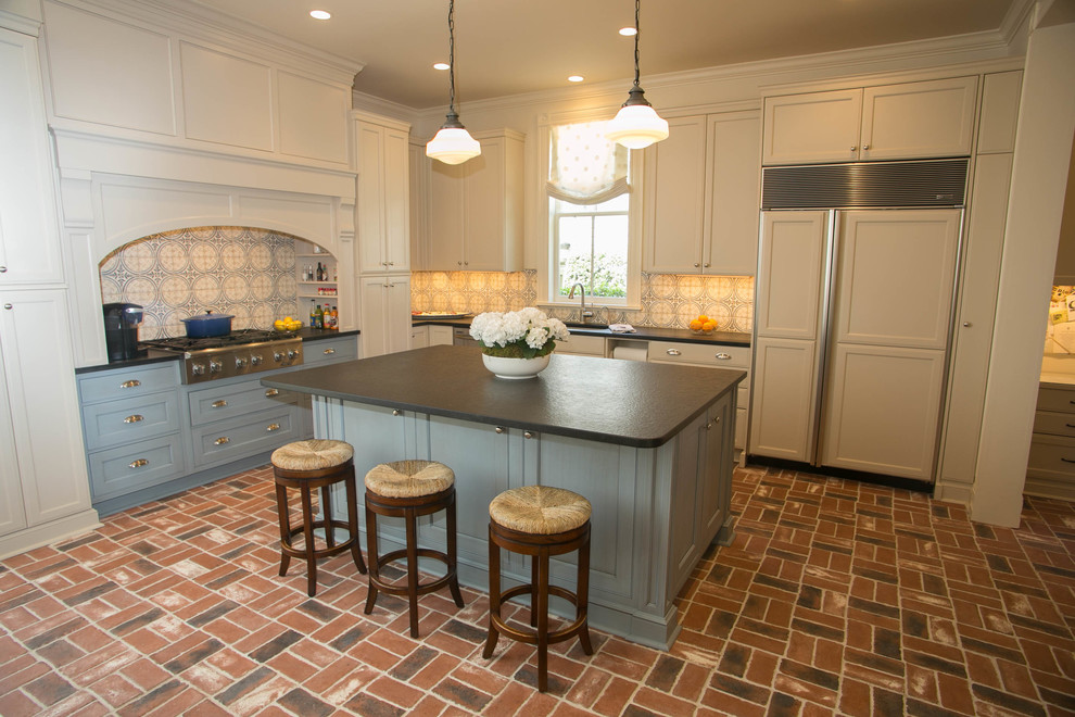 Foto di una cucina classica di medie dimensioni con lavello sottopiano, ante con riquadro incassato, elettrodomestici in acciaio inossidabile e pavimento in mattoni