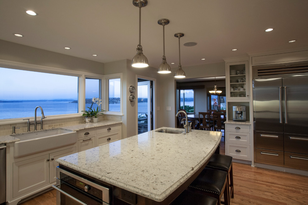 Example of a large classic single-wall medium tone wood floor eat-in kitchen design in Seattle with a farmhouse sink, shaker cabinets, white cabinets, quartz countertops, white backsplash, subway tile backsplash, colored appliances and an island