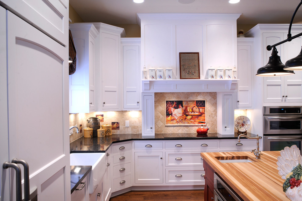 Example of a mountain style u-shaped medium tone wood floor and exposed beam eat-in kitchen design with shaker cabinets, white cabinets, wood countertops, beige backsplash and paneled appliances