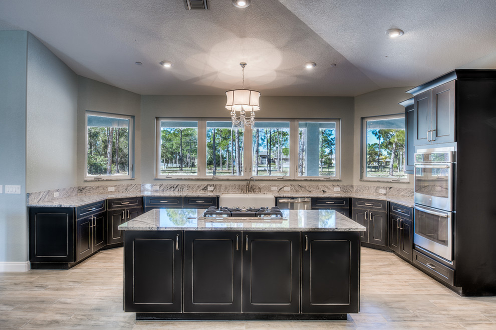 Eat-in kitchen - large contemporary u-shaped porcelain tile eat-in kitchen idea in Miami with a farmhouse sink, recessed-panel cabinets, distressed cabinets, granite countertops, stainless steel appliances, two islands, gray backsplash and stone slab backsplash