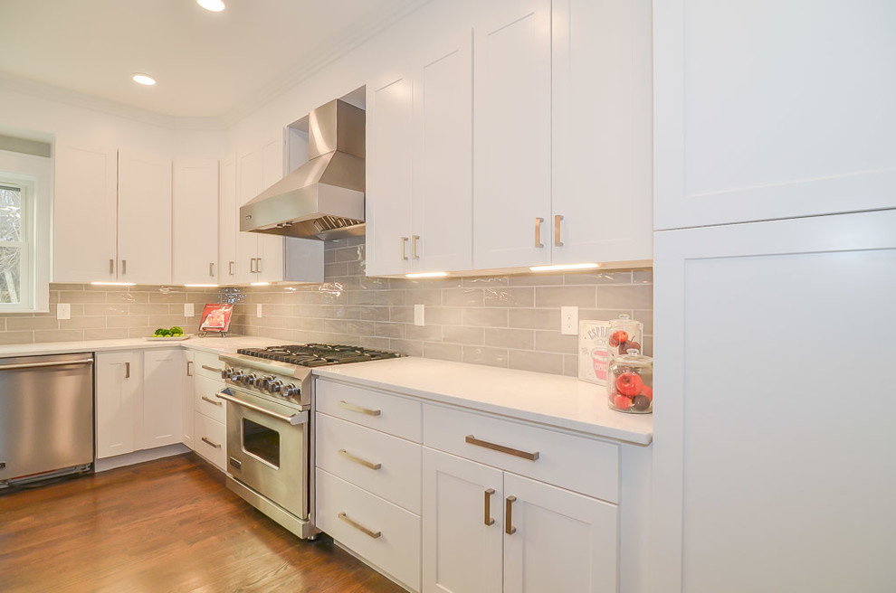 ボストンにある高級な広いモダンスタイルのおしゃれなキッチン (アンダーカウンターシンク、シェーカースタイル扉のキャビネット、グレーのキャビネット、クオーツストーンカウンター、グレーのキッチンパネル、セラミックタイルのキッチンパネル、シルバーの調理設備、無垢フローリング、黄色い床、白いキッチンカウンター) の写真