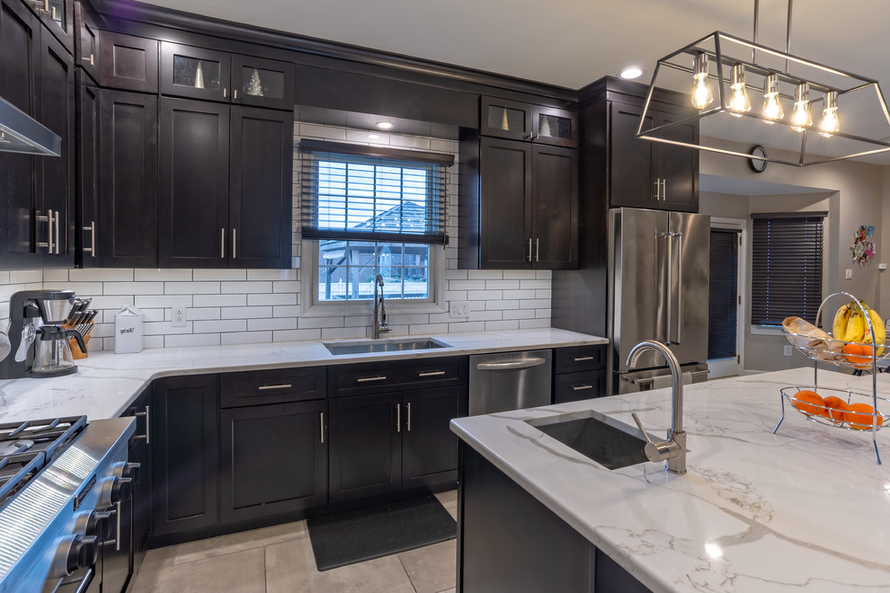 Large transitional l-shaped porcelain tile and gray floor eat-in kitchen photo in Philadelphia with an undermount sink, shaker cabinets, dark wood cabinets, quartz countertops, white backsplash, subway tile backsplash, stainless steel appliances, an island and white countertops