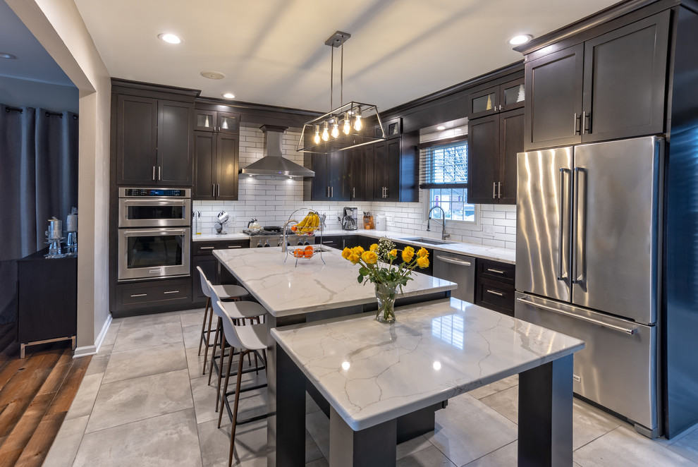 Eat-in kitchen - large transitional l-shaped porcelain tile and gray floor eat-in kitchen idea in Philadelphia with an undermount sink, shaker cabinets, dark wood cabinets, quartz countertops, white backsplash, subway tile backsplash, stainless steel appliances and white countertops