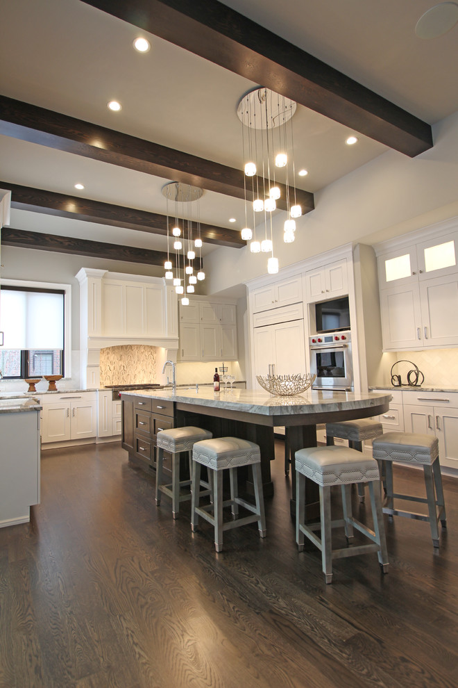Expansive traditional u-shaped kitchen/diner in Detroit with a submerged sink, shaker cabinets, white cabinets, engineered stone countertops, white splashback, stone tiled splashback, stainless steel appliances, dark hardwood flooring, an island, brown floors and grey worktops.