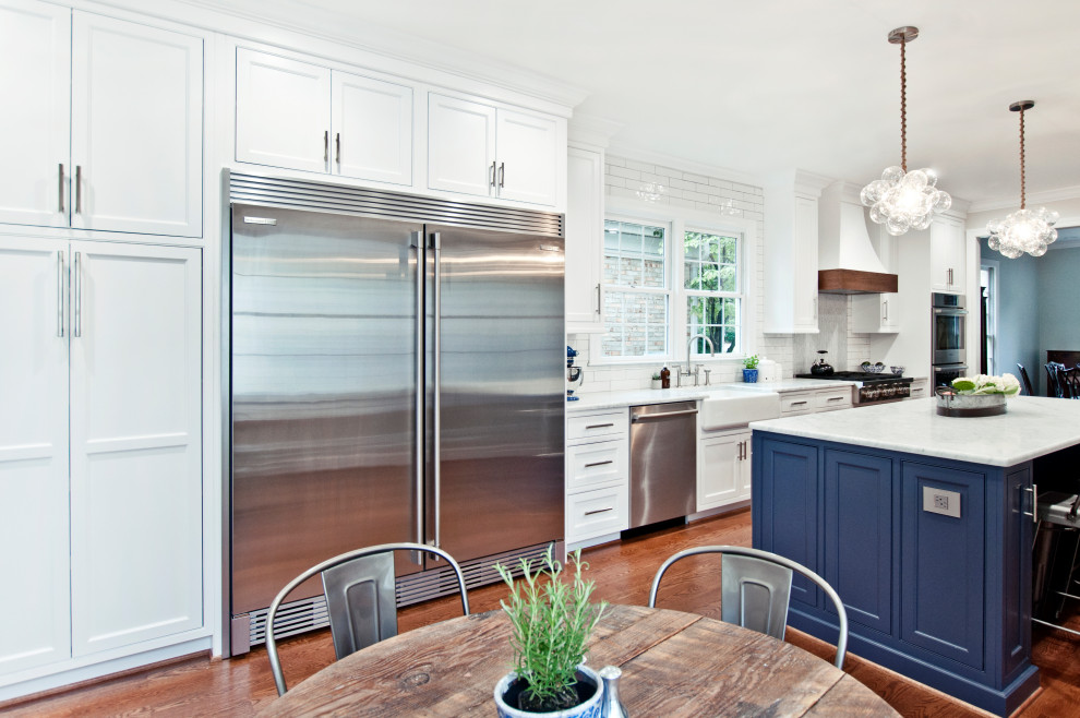 Huge cottage galley medium tone wood floor and brown floor open concept kitchen photo in Nashville with a farmhouse sink, beaded inset cabinets, white cabinets, marble countertops, white backsplash, cement tile backsplash, stainless steel appliances, an island and white countertops