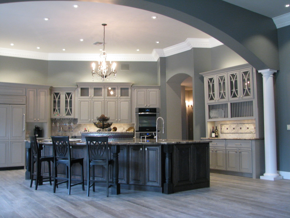 Inredning av ett klassiskt mycket stort kök, med en undermonterad diskho, luckor med upphöjd panel, grå skåp, granitbänkskiva, grått stänkskydd, stänkskydd i stenkakel, rostfria vitvaror, klinkergolv i porslin och en köksö