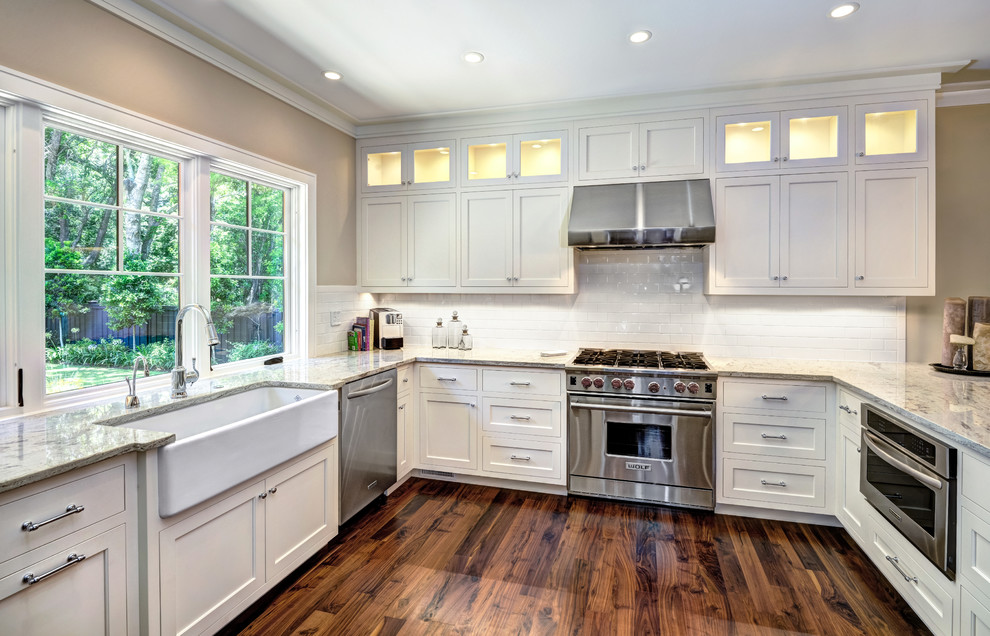 Photo of a medium sized traditional u-shaped kitchen/diner in Charleston with a belfast sink, shaker cabinets, white cabinets, white splashback, metro tiled splashback, stainless steel appliances and an island.