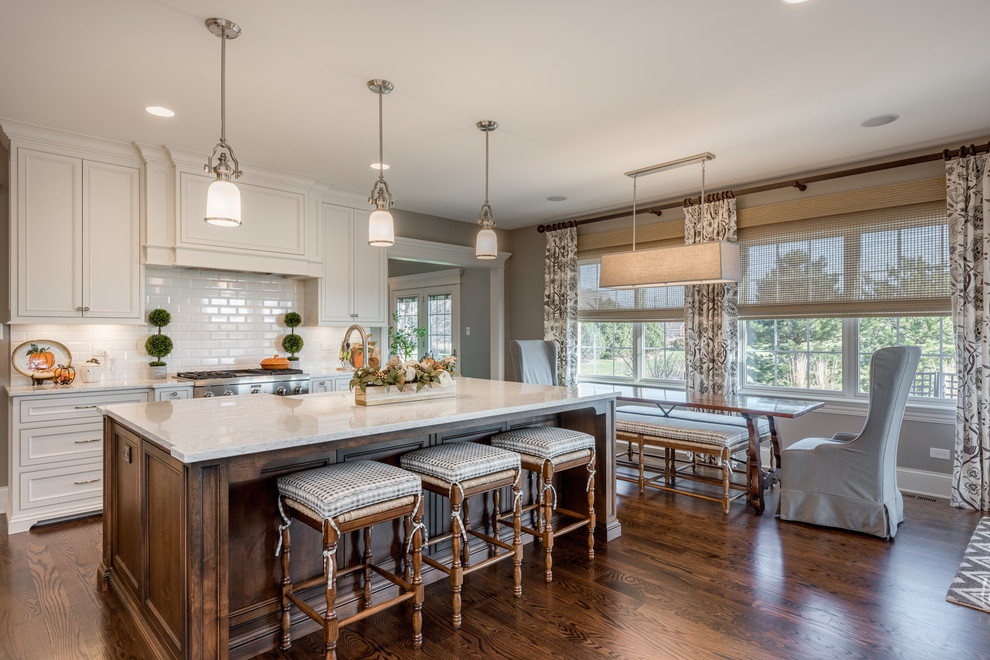 Example of a large classic l-shaped dark wood floor and brown floor eat-in kitchen design in Chicago with a farmhouse sink, flat-panel cabinets, white cabinets, quartzite countertops, white backsplash, porcelain backsplash, paneled appliances, an island and white countertops