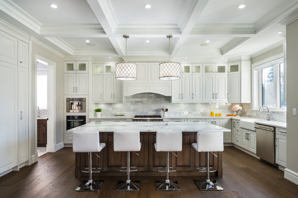 Huge elegant l-shaped dark wood floor and brown floor eat-in kitchen photo in Vancouver with a farmhouse sink, raised-panel cabinets, white cabinets, marble countertops, white backsplash, marble backsplash, stainless steel appliances, an island and white countertops