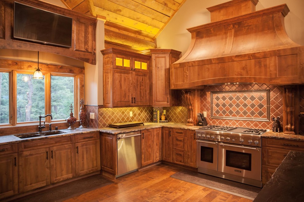 Photo of a medium sized rustic u-shaped enclosed kitchen in Albuquerque with a double-bowl sink, shaker cabinets, medium wood cabinets, granite worktops, multi-coloured splashback, ceramic splashback, stainless steel appliances, dark hardwood flooring, a breakfast bar and brown floors.